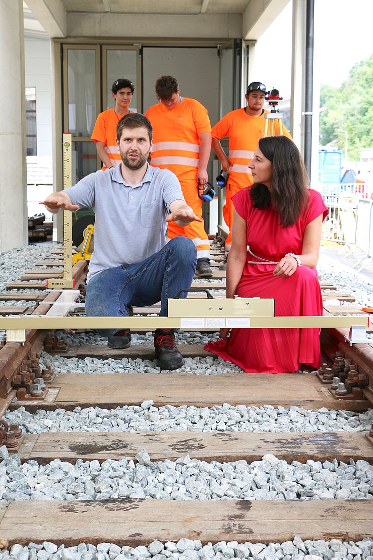 Bahngleise, Mann erklärt Kircher mit Gesten etwas