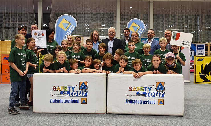 Foto Siegerehrung: Die Kinder der 3. Klasse der Volksschule Mieming-Barwies stehen in grünen T-Shirts in zwei Reihen hinter einem weißen Podest und freuen sich über den zweiten Platz. 