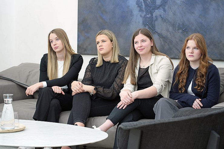 Vier junge Frauen sitzen auf einem Sofa.