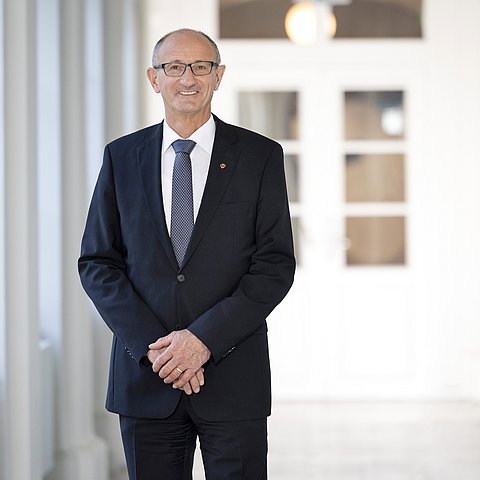 Porträt von HLH Mattle in einem großen, weißen Gang im Landhaus.