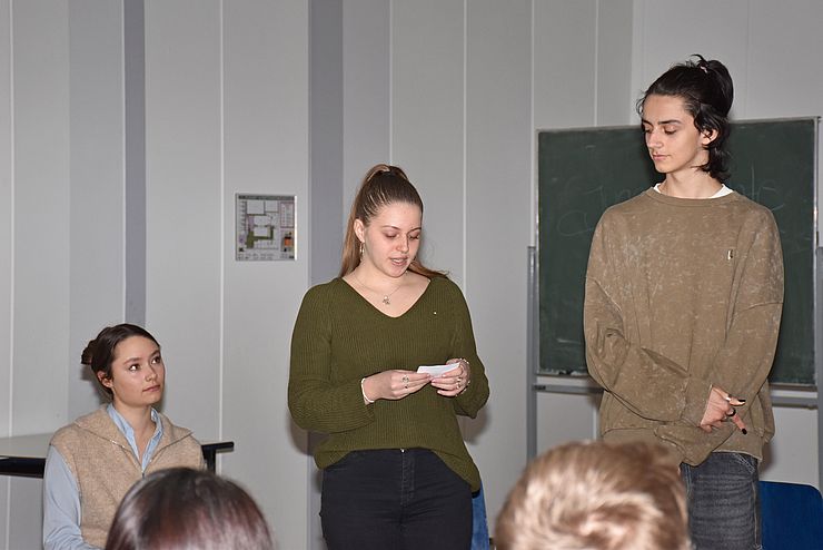 SchülerInnen, die am Podium teilnehmen: Mädchen in der Mitte liest von Zettel ab
