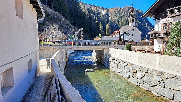 Bagger auf Brücke über Bach