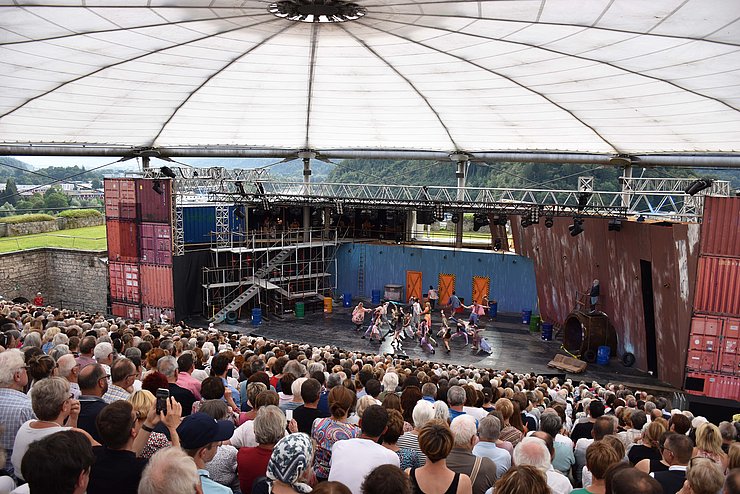 Blick von hinten über Menschenmenge auf Bühne - tanzende SchauspielerInnen