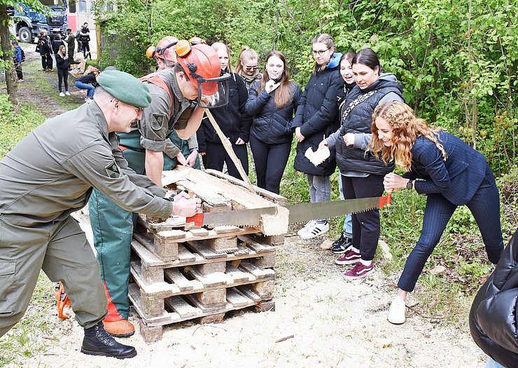 Ein Mann und eine Frau sägen einen Holzstamm ab.