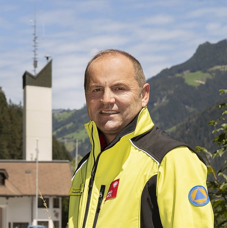 © Land Tirol/Die Fotografen Landeshauptmannstellvertreter Geisler in gelber Einsatzjacke im Freien