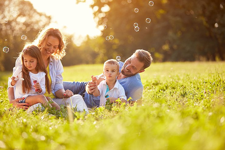 Familie sitzt auf einer Wiese