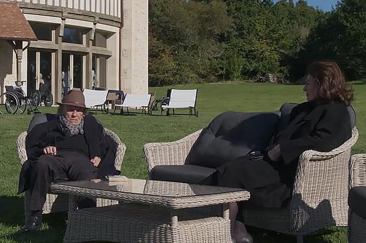 Ein älteres Ehepaar sitzt auf Gartenmöbeln im Garten und redet miteinander.