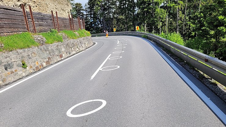 Weiße Ellipsen auf Asphalt in einer engen Kurve