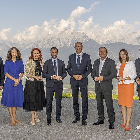 Gruppenfoto der Regierungsmitglieder. Im Hintergrund ist eine Gebirgskette zu sehen.