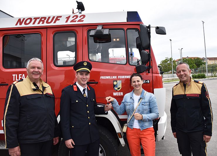 Alfons Gruber, Stipe Batur, Landesrätin Astrid Mair und Jakob Unterladstätter stehen vor dem Feuerwehrauto. Dabei übergibt die Landesrätin die Schlüssel an den Feuerwehrkommandanten Batur.