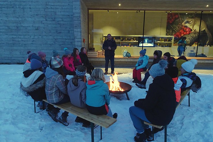 Gruppe von Kindern sitzt um ein Lagerfeuer