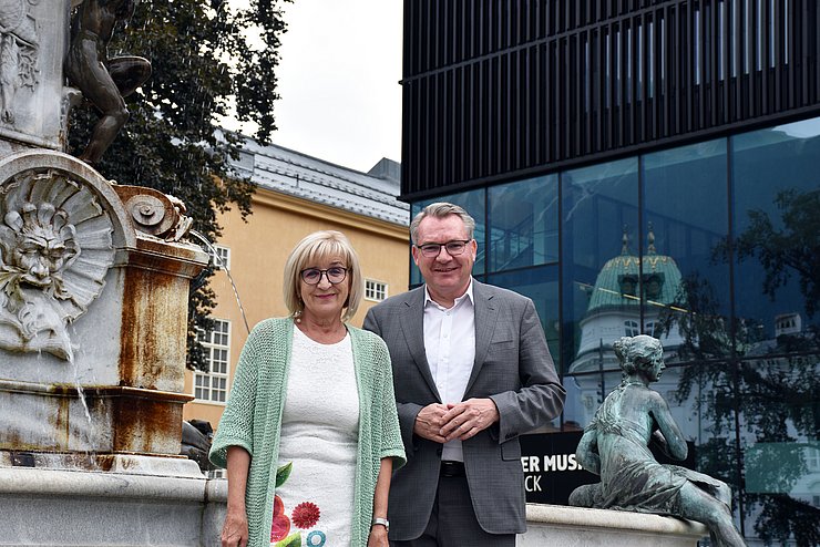 LRin Palfrader und LR Tratter vor Leopoldsbrunnen und Haus der Musik in Innsbruck stehend