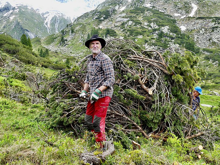 © Naturpark Zillertaler Alpen Mann vor großem Haufen Ästen