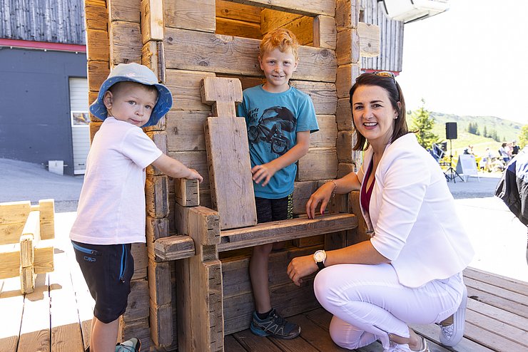 drei Personen vor einer Holz-Spieleaktion des Familienfestes