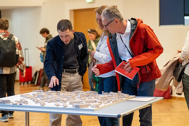 © Keser/BMWKMS Menschen schauen sich ein Architekturmodell an