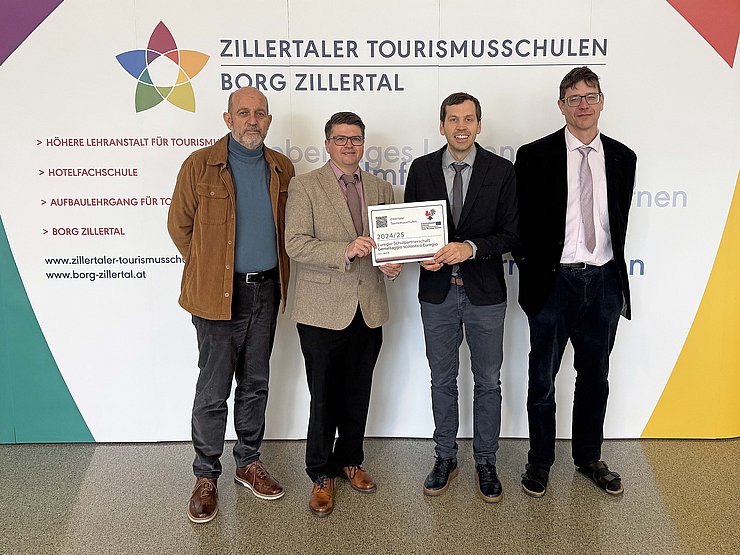 Personen halten Aufkleber, stehen vor Plakat der Schule