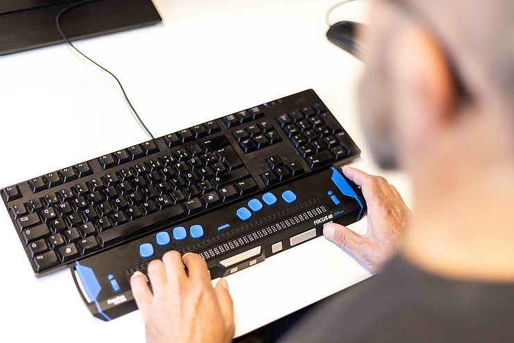 Mann nutzt Screenreader, angeschlossen an Tastatur