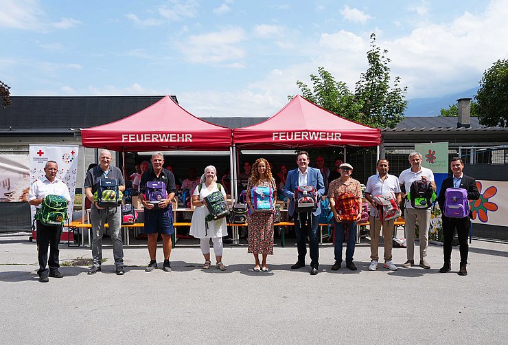 © Land Tirol/Dorfmann Personen stehen nebeneinander - mit Schultaschen in den Händen