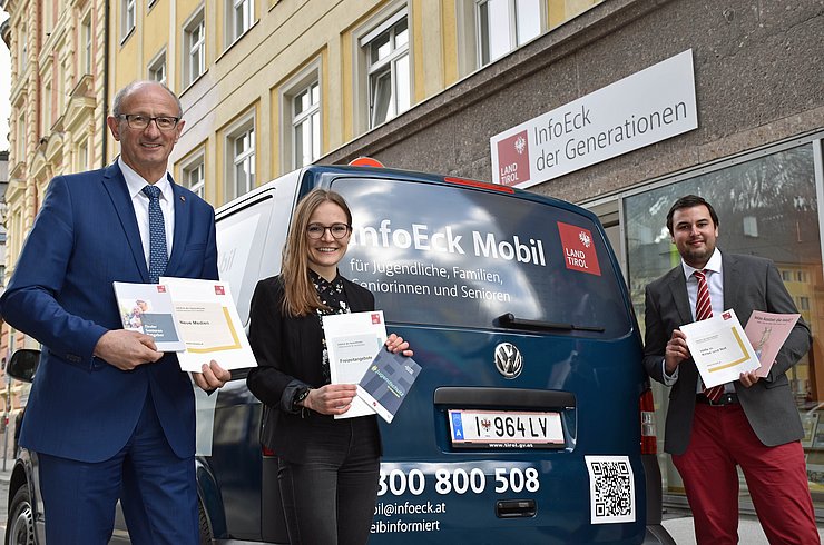 Landesrat Anton Mattle mit einer InfoEck-Mitarbeiterin und dem Geschäftsführer des InfoEck mit Broschüren in der Hand vor dem InfoEck Mobil