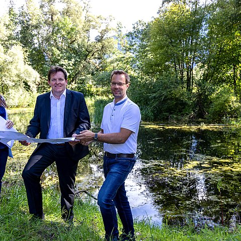 Auf dem Bild sind Stefanie Holzer von Revital, LR René Zumtobel und Projektleiter Gernot Guggenberger vor dem Teich zu sehen