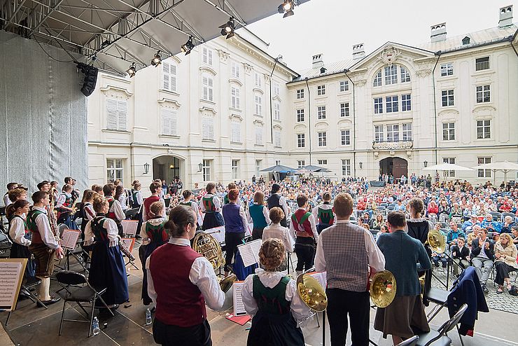 Bild vom Konzert mit den Musikerinnen und Musikern auf der Bühne und vor der Bühne mit vielen Zuschauerinnen und Zuschauern im Innenhof der Innsbrucker Hofburg.