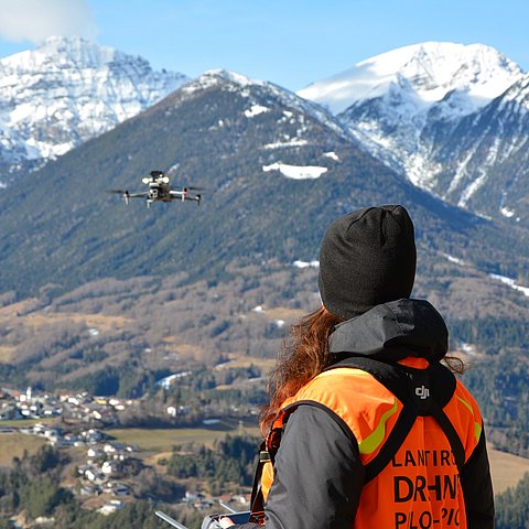 Frau mit Weste steuert Drohne