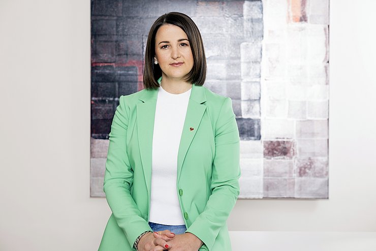 Landesrätin Astrid Mair im Büro auf ihrem Schreibtisch sitzend
