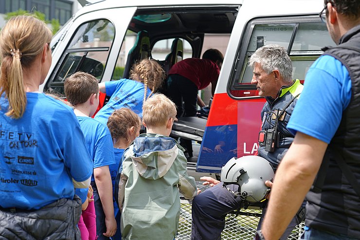 Kinder steigen in einen Helikopter ein.
