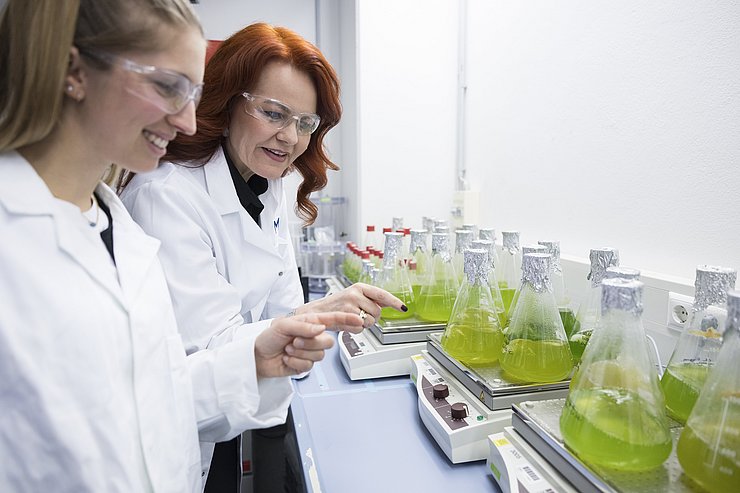 © Land Tirol/Sedlak zwei Frauen im Laborkittel vor Reagenzgläser mit grüner Flüssigkeit