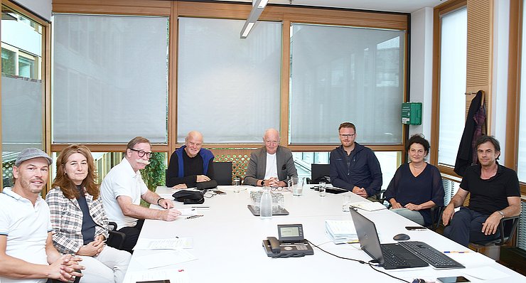 Die TeilnehmerInnen der Sitzung um einen Tisch herum sitzend
