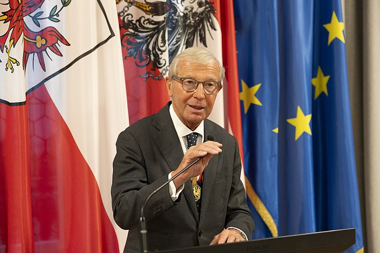 © Land Tirol/Sedlak Ein Mann greift an ein Standmikrofon.