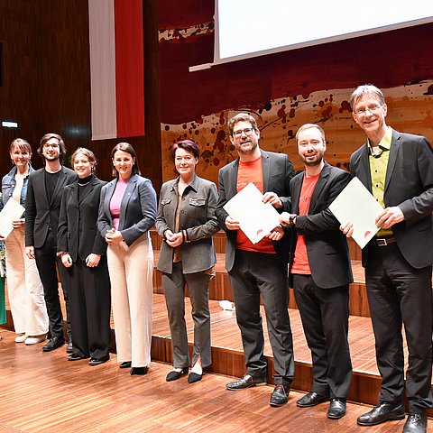 Gruppenfoto der Chorleiter mit Jugendlandesrätin Astrid Mair und Landtagspräsidentin Sonja Ledl-Rossmann: Alle stehen auf der Bühne im Saal Tirol des Congress Innsbruck, als Wandschmuck hinten die Landesfahne.