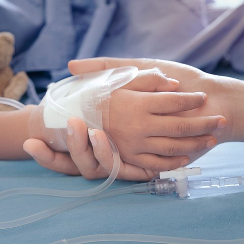 Hand eines Kindes mit intravenösem Zugang