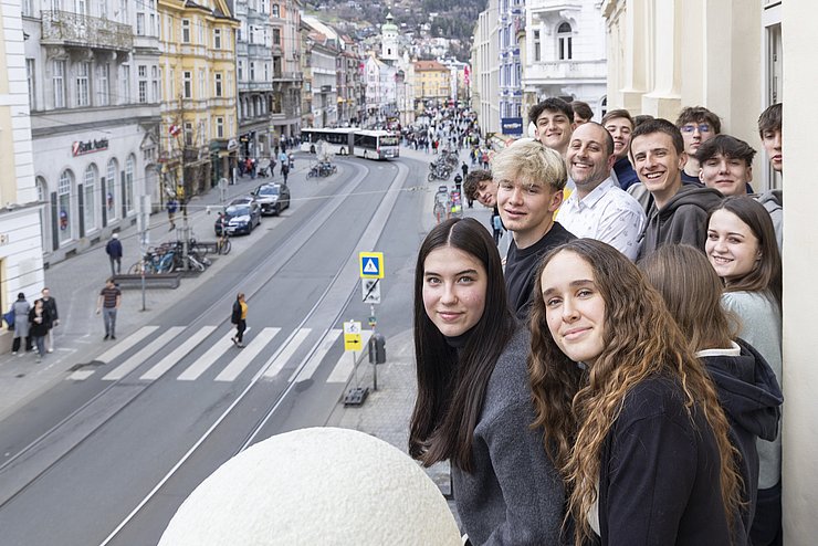 Mehrere Menschen stehen an einem Balkon.