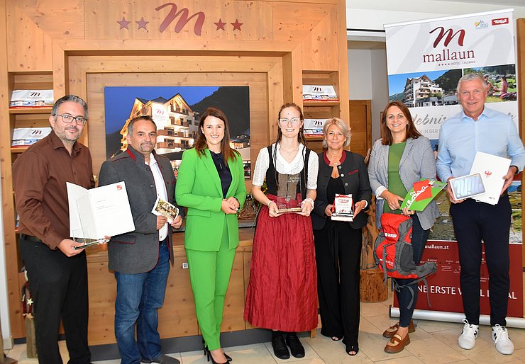 V. li. bei der Auszeichnungsfeier im Hotel Mallaun in See Christoph Mallaun (Hotelchef), Michael Zangerl (Bgm See), Arbeits- und Jugendlandesrätin Astrid Mair, „Lehrling des Monats Juli 2025“ Selina Karin Narr, Martina Bombardelli (Direktorin Tiroler Fachberufsschule für Tourismus und Handel Landeck), Stephanie Fritz (stellvertretende Bezirksstellenleiterin Wirtschaftskammer Landeck) und Stefan Scherl (Kammerrat Arbeiterkammer Tirol).       
