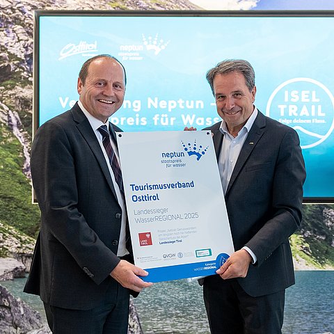 Zwei Menschen halten eine Urkunde in der Hand.