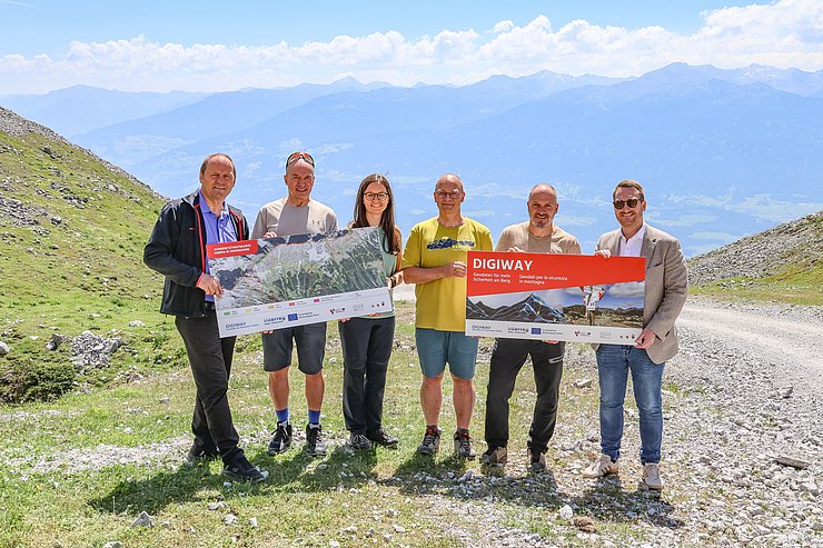 © Land Tirol/Wurnig Personen stehen nebeneinander mit Schildern vor Bergkulisse