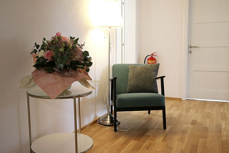 Bild von Stuhl mit Tisch im Gang einer Wohnung im Frauenhaus. 