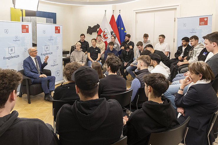 Viele Menschen sitzen in einem Raum und sprechen miteinander.