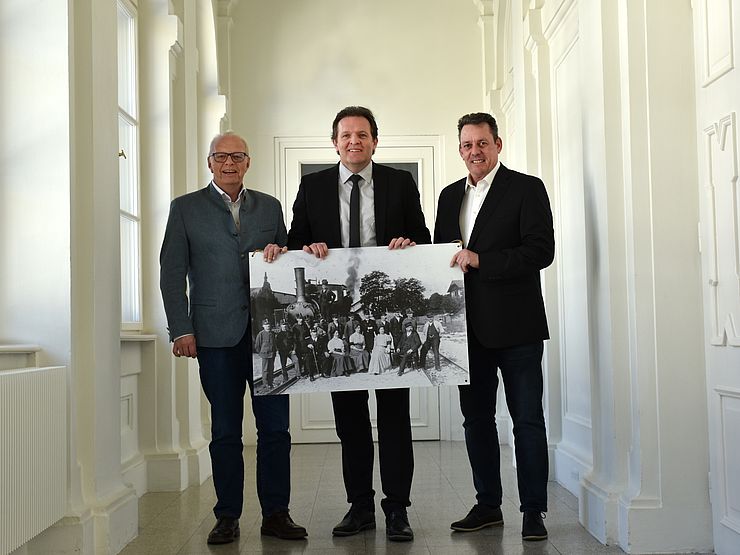 Gruppenbild mit großem schwarz-weiß Foto in der Hand