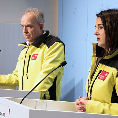 Mair und Rizzoli in gelben Jacken bei der PK stehend