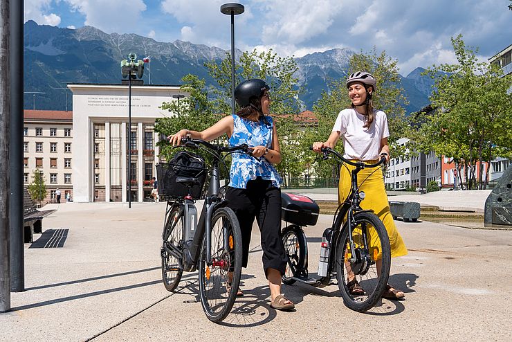 Zwei junge Frauen mit E-Bike stehend am Landhausplatz
