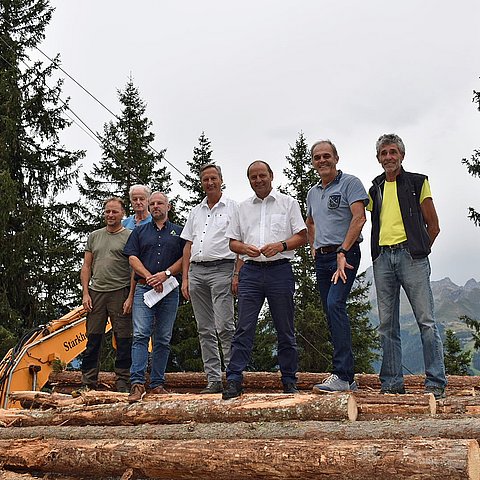 Beim Lokalaugenschein im Finkenberger Schutzwald steht eine Gruppe von Personen auf einem Stapel von gefällten Baumstämmen: von links Waldaufseher Michael Erler, Agrargemeinschaftsobmann Johann Stöckl, Ivo Schreiner, Wildbach- und Lawinenverbauung Tirol, Landesforstdirektor Josef Fuchs, LHStv Josef Geisler, Bgm Andreas Kröll und Norbert Mitterer, Obmannstellvertreter der Agrargemeinschaft.