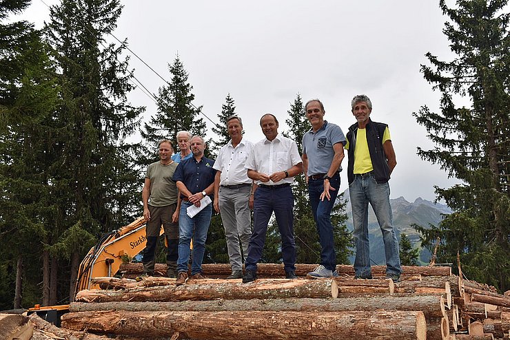 Beim Lokalaugenschein im Finkenberger Schutzwald steht eine Gruppe von Personen auf einem Stapel von gefällten Baumstämmen: von links Waldaufseher Michael Erler, Agrargemeinschaftsobmann Johann Stöckl, Ivo Schreiner, Wildbach- und Lawinenverbauung Tirol, Landesforstdirektor Josef Fuchs, LHStv Josef Geisler, Bgm Andreas Kröll und Norbert Mitterer, Obmannstellvertreter der Agrargemeinschaft.