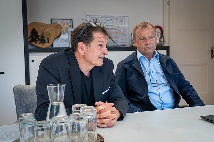 © Land Tirol/Neuner Zwei Herren sitzen nebeneinander an einem Tisch.