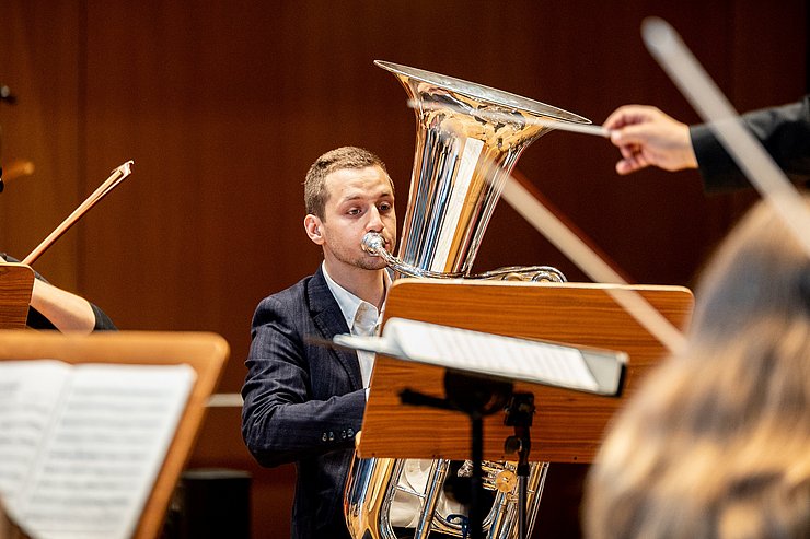 Ein Tubist wird von einem Orchester begleitet.