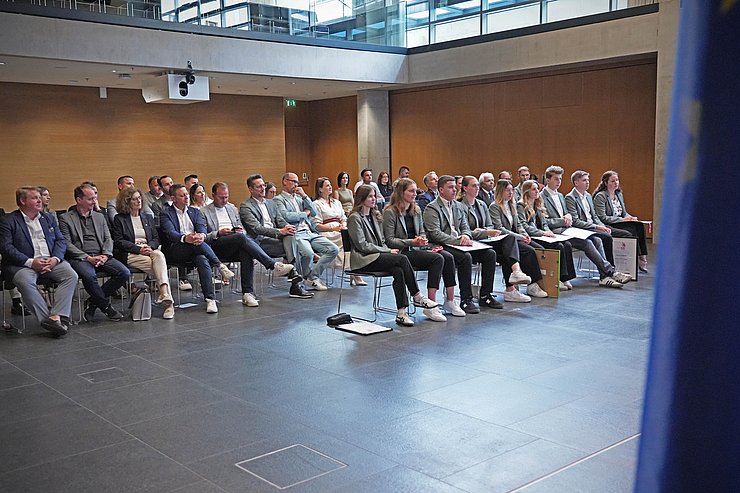 © Land Tirol/Schallhart Menschen sitzen in einem Saal