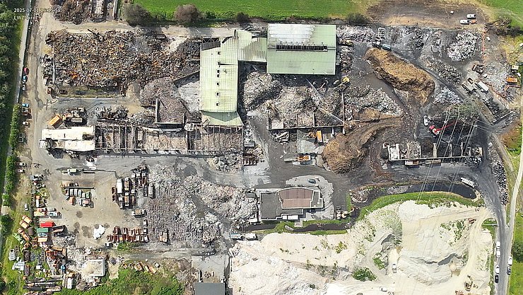© Land Tirol/Drohnen-Einsatz-Gruppe Blick von oben auf einen abgebrannten Recyclinghof. Mittig oben befinden sich große Hallen. Drumherum befindet sich abgebranntes Deponiematerial.