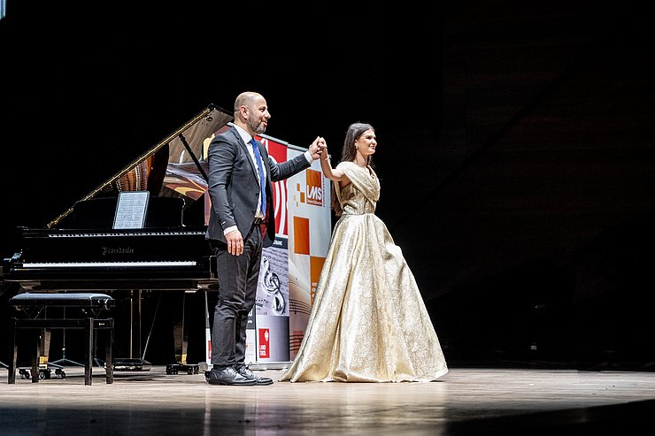 Die Sängerin reicht dem Korrepetitor die Hand und verbeugt sich.