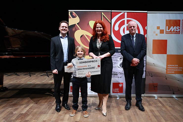 Drei Erwachsene mit einem jungen Preisträger.